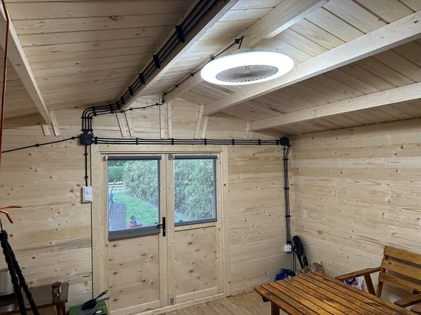 Domek ogrodowy z okrągłą oprawą LED i instalacją natynkową wokół drzwi